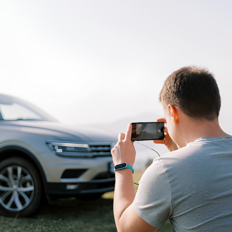 A person taking a photo of a car, presumably detailing or inspecting it for sale