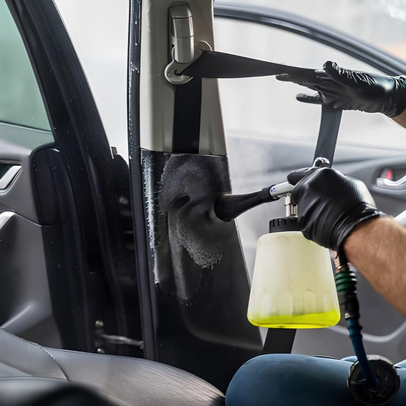 Person cleaning interior of a car using a cloth and spray bottle.