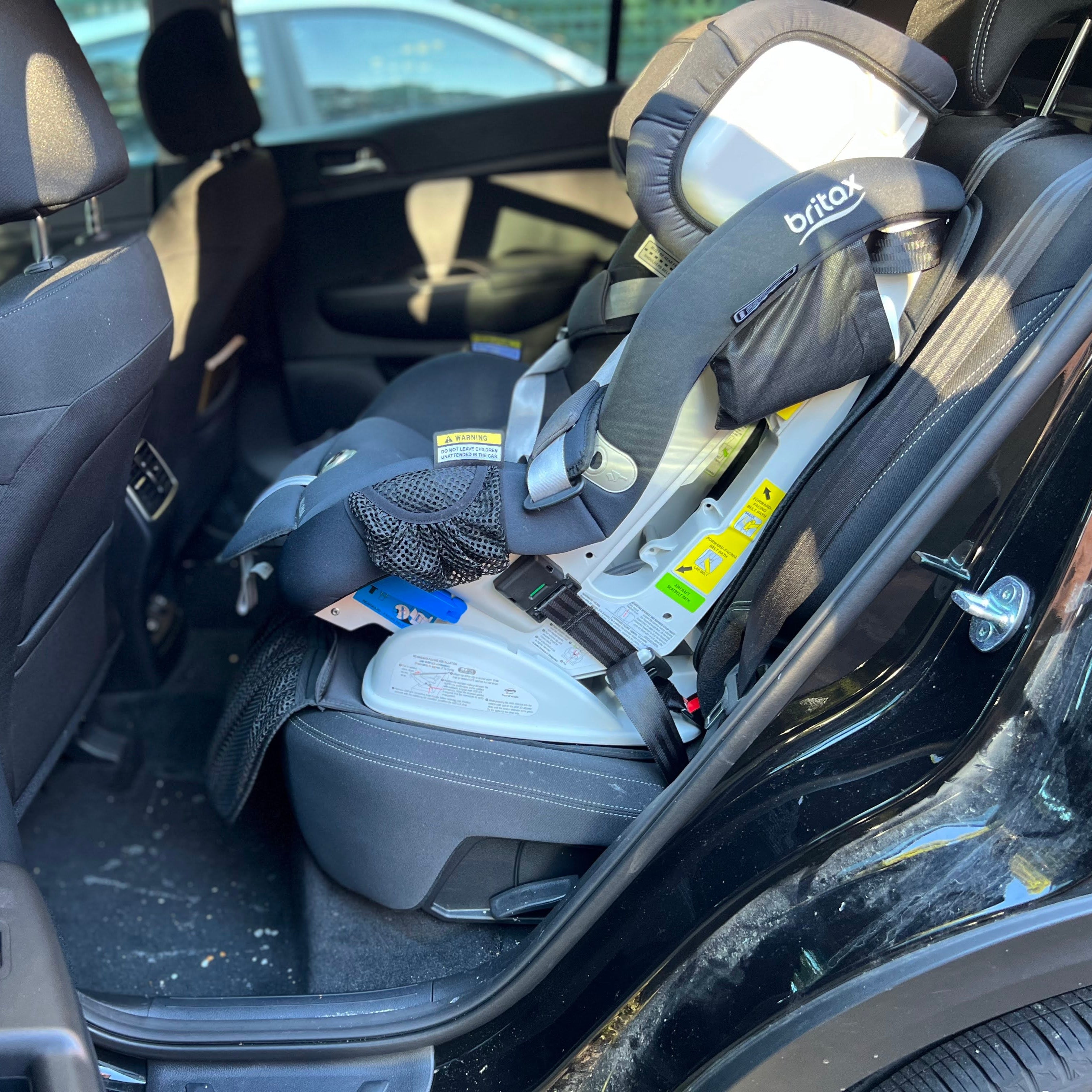 A car seat with a child safety seat installed, showing signs of dirt and grime, indicating it needs cleaning.
