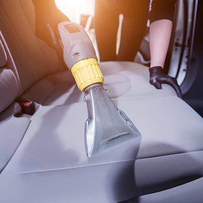 A steam cleaning device being used on a car seat, illustrating the process of steam cleaning.